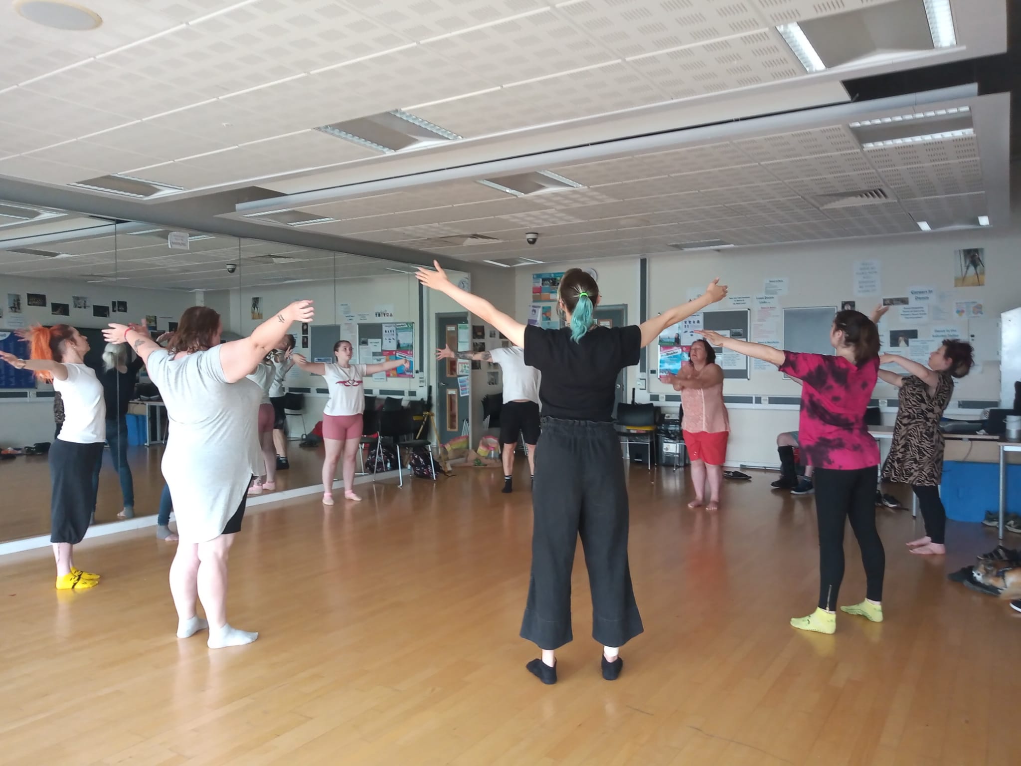 Group of Fallen Angels dancers in a circle with arms raised