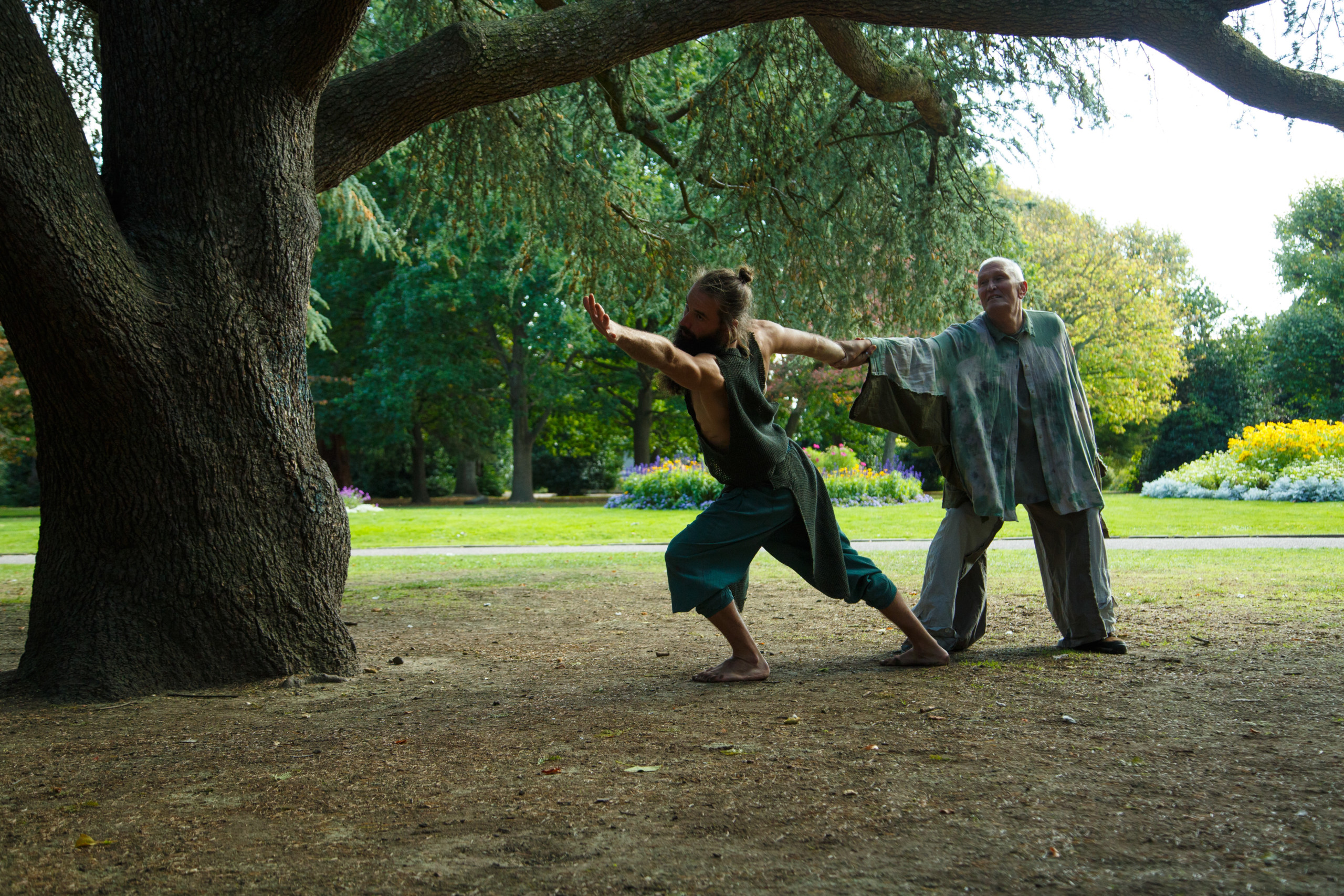 a male dancer reaches away as another male dancer holds and supports him
